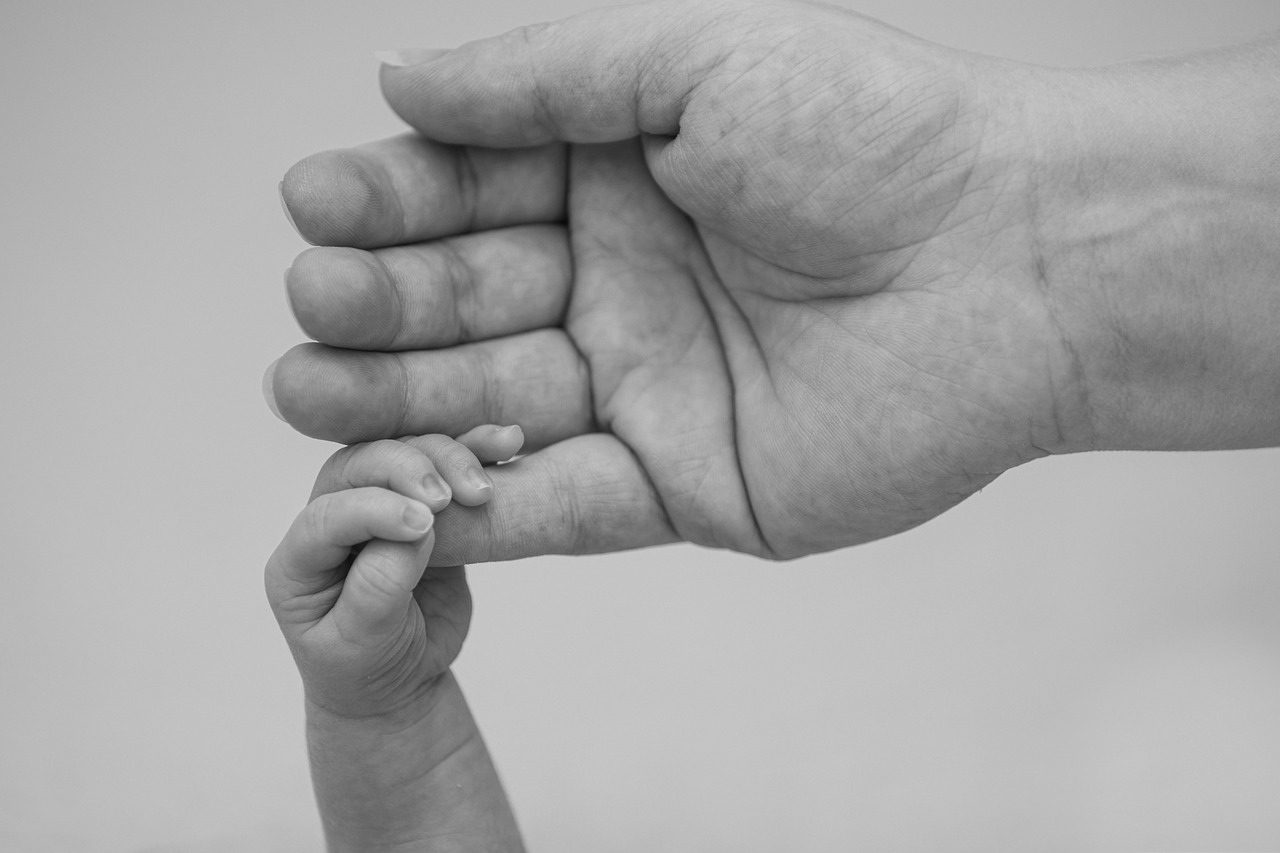 Newborn's hand holding a parent's finger